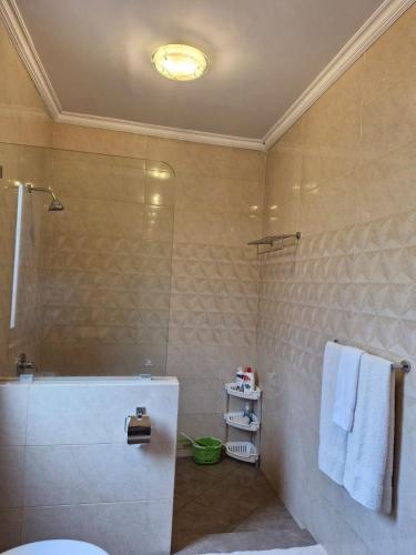 a bathroom with a shower and a toilet and towels at Sari Ayuning Nusa Guest House in Nusa Lembongan
