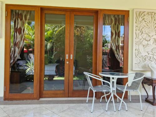 a table and chairs in front of a glass door at Sari Ayuning Nusa Guest House in Nusa Lembongan