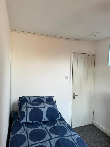 a bedroom with a bed with blue and white pillows at Wembley property in London