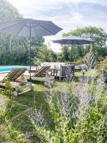 un patio avec deux parasols et une piscine dans l'établissement Domaine de pragelier, à Tourtoirac