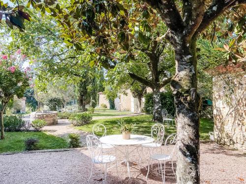 une table et des chaises sous un arbre dans un jardin dans l'établissement Domaine de pragelier, à Tourtoirac