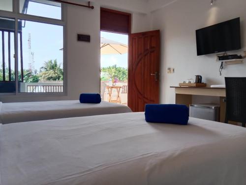 una camera d'albergo con due letti e una televisione di Hanifaru Beach Inn ad Atollo Baa