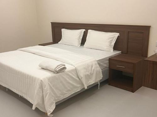 a large bed with white sheets and a night stand at ريزا الفندقية Reeza Suites in Al Khobar