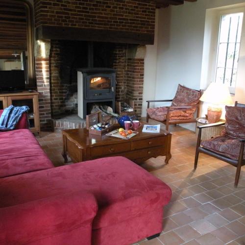 sala de estar con sofá rojo y chimenea en ECODOMAINE COEUR DE NORMANDIE, en Saint-Aubin-de-Bonneval