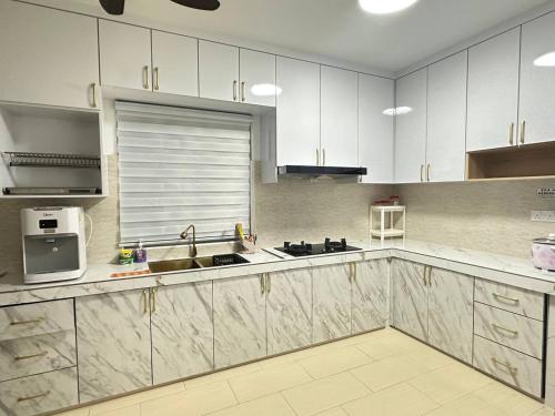 a kitchen with white cabinets and a sink and a microwave at Amir Homestay in Yong Peng