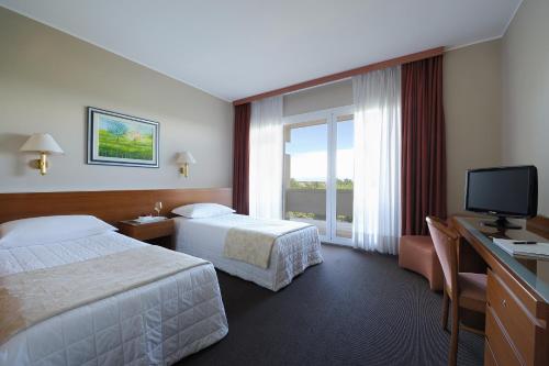 a hotel room with two beds and a television at Hotel Des Bains Terme in Montegrotto Terme