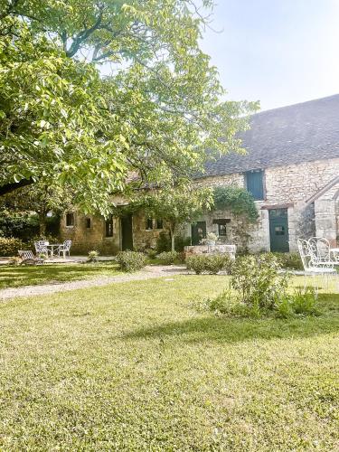 une maison en pierre avec une cour dotée de chaises et d'un arbre dans l'établissement Domaine de pragelier, à Tourtoirac