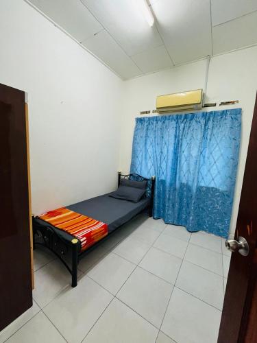 a small room with a bed with a blue curtain at Homestay Mama in Kampong Alor Gajah