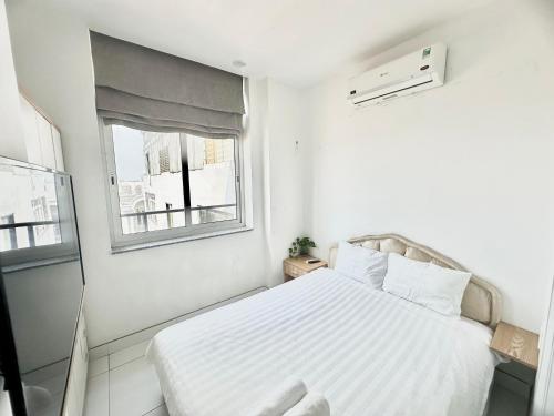 a white bedroom with a bed and a window at Aloha House Apartment in Ho Chi Minh City