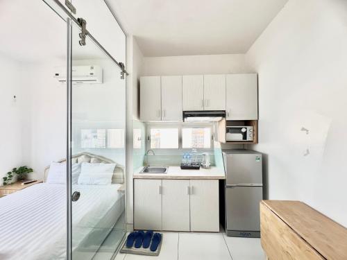 a small kitchen with a bed and a refrigerator at Aloha House Apartment in Ho Chi Minh City