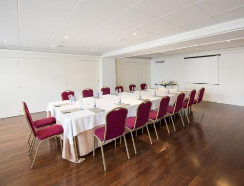 a conference room with a long table and red chairs at Hotel Almirante in Ferrol