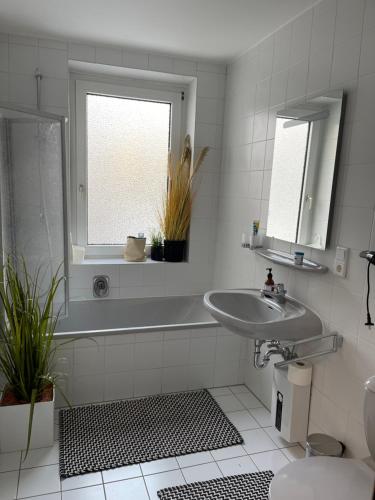 a white bathroom with a sink and a window at Zimmer in der Altstadt in Bielefeld