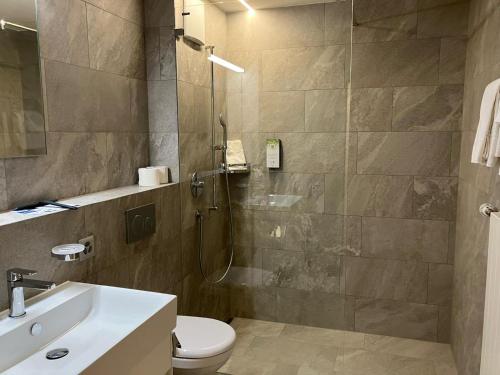 a bathroom with a shower and a toilet and a sink at Hotel Conrad in Scuol