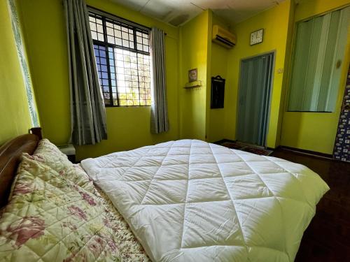 ein Schlafzimmer mit einem weißen Bett in einem Zimmer mit gelben Wänden in der Unterkunft Kulim Hi-Tech Hospital Homestay in Kulim