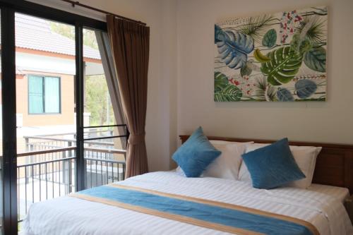 a bed with blue pillows in a room with a window at WangTanChiangMai PoolVilla精品泳池别墅 in Chiang Mai