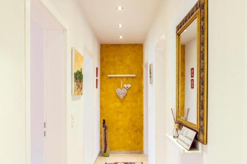 a hallway with a yellow wall and a mirror at Weinbau Frank Schönig in Sommerhausen