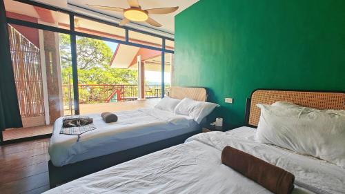 Duas camas num quarto com uma parede verde em 80 Bar Hostel em Coron