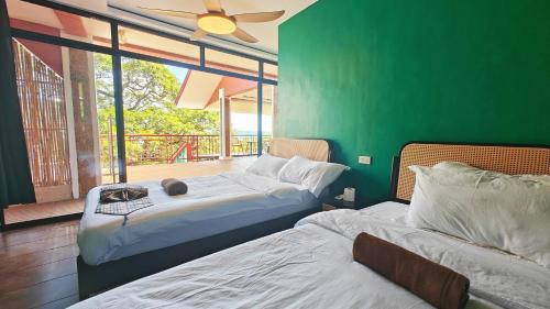 two beds in a room with a green wall at 80 Bar Hostel in Coron