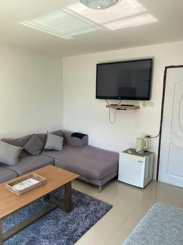a living room with a couch and a flat screen tv at English owned Homestay and Yoga in Chalong 