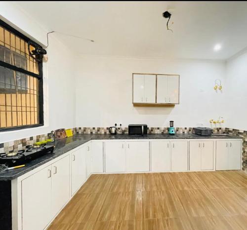 an empty kitchen with white cabinets and a wooden floor at Centaurus Pvt. villa with lawn in Noida