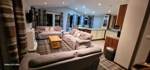 a large living room with couches and a kitchen at Castlewood lodge in Banchory