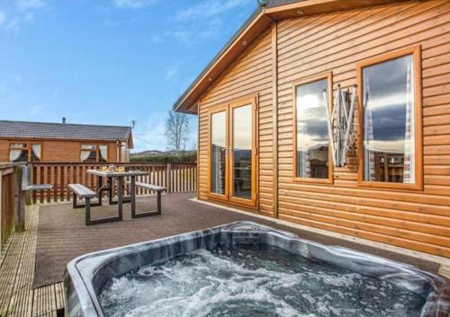 a hot tub on a deck next to a house at Castlewood lodge in Banchory