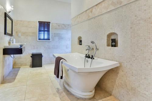 Baño blanco con bañera y lavamanos en Grandiose 4 BR Sea Facing Villa, en Cap Estate