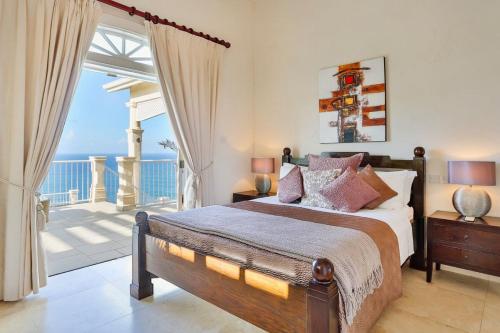 a bedroom with a bed and a balcony with the ocean at Grandiose 4 BR Sea Facing Villa in Cap Estate