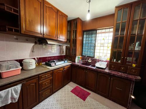 une cuisine avec des placards en bois et un tapis rose dans l'établissement Kulim Hi-Tech Hospital Homestay, à Kulim