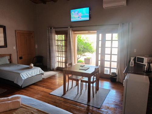 a bedroom with a bed and a table and a television at Featherhouse in Colesberg
