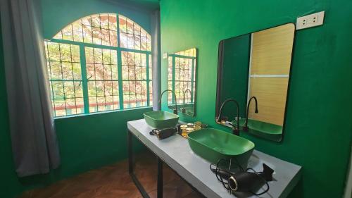 a green bathroom with a sink and a mirror at 80 Bar Hostel in Coron