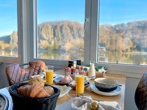 - une table avec de la nourriture pour le petit-déjeuner, du jus d'orange et une fenêtre dans l'établissement Mes Caprices B&B Villa Mosan Bord de Meuse, à Namur