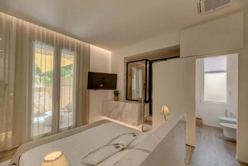 a white bedroom with a large bed and a bathroom at Le Palmette Suites in Cagliari