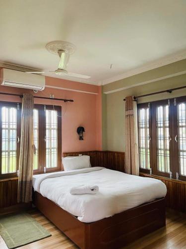 1 dormitorio con 1 cama grande y ventanas en sauraha alley inn en Chitwan