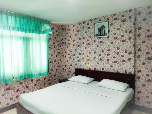 um quarto com duas camas e uma parede com flores em Woodlands Inn em Bangkok