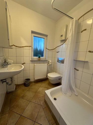 a bathroom with a sink and a tub and a toilet at Villa Baltica Bungalow in Dahme