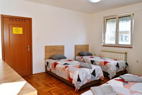 a room with two beds and a door at Guest House Sani in Skopje