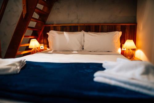 a bed with two lamps and a blue blanket at Espaço Villa Verde in Ibiúna