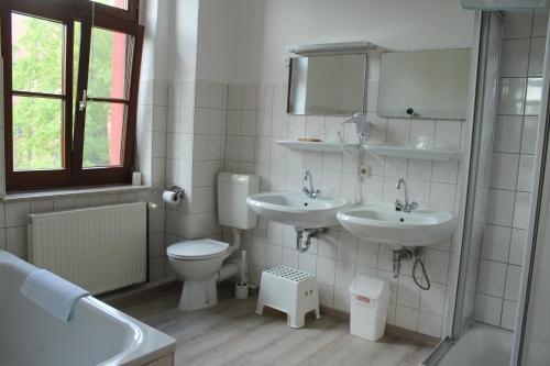 ein Badezimmer mit zwei Waschbecken, einem WC und einem Spiegel in der Unterkunft Landhotel Storchenkrug in Rühstädt