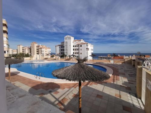 uma piscina com um guarda-sol e alguns edifícios em Costamar playa arenales del sol em Arenales del Sol