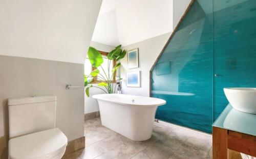 a bathroom with a tub and a toilet and a sink at 5-Bedroom House with a Stunning Pool, Expansive Garden, Trampoline, and Swings in Shepperton