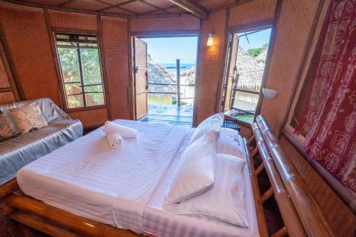 a bedroom with a bed and a couch and windows at Pareehut Resort Koh Sichang in Ko Si Chang