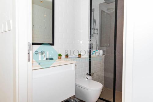 a white bathroom with a toilet and a mirror at Grandeur Studio In Pixel in Abu Dhabi