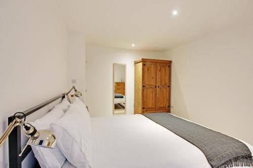 a bedroom with a white bed and a wooden cabinet at Brook Terrace in Luddenden Foot