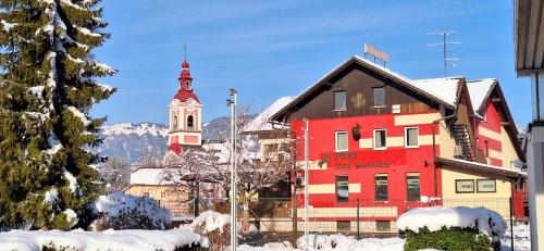 a red building with a clock tower and a church at PONI NAKLO - Sobe Marinšek in Naklo