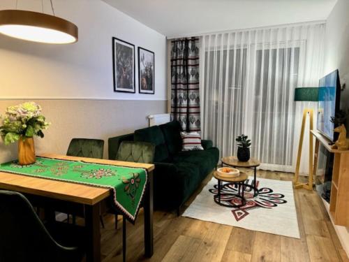 a living room with a green couch and a table at Panorama Karkonoszy - Apartamenty KOMFORT z widokiem na Śnieżkę i Aquapark in Karpacz
