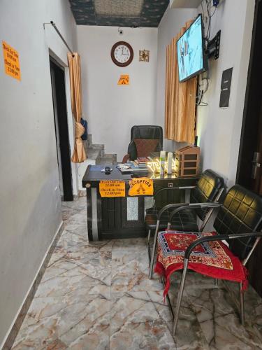 ein Wohnzimmer mit einem Tisch, Stühlen und einem TV in der Unterkunft Shri Radha Rani Bhawan in Vrindāvan