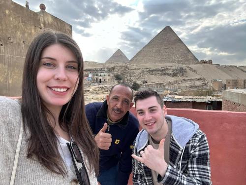 three people posing for a picture in front of the pyramids at Energy Of Pyramid Hotel in Cairo