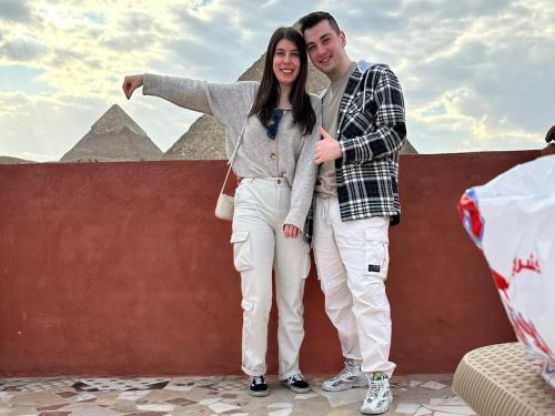 a man and a woman standing in front of the pyramids at Energy Of Pyramid Hotel in Cairo