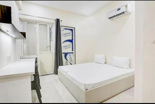 um quarto branco com uma cama e uma secretária em GAURA NITAI GUEST HOUSE em Dahmi